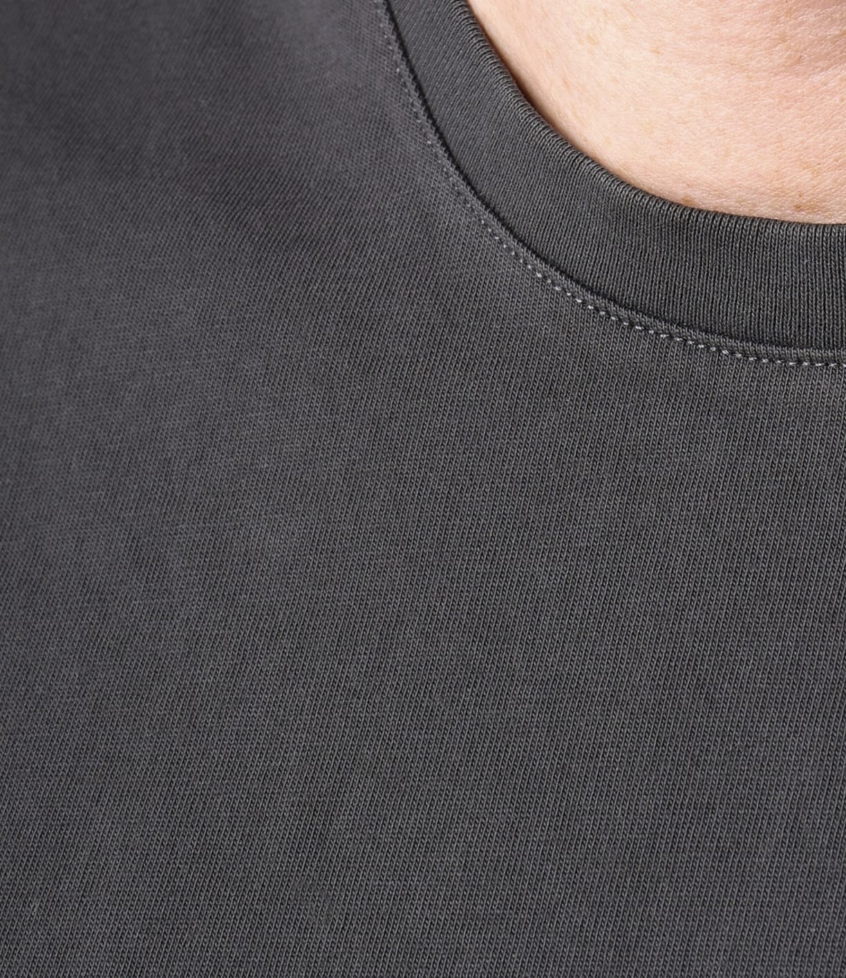 Close-up of the collar and upper chest of the Best Made Co Standard T-Shirt in Faded Black, showcasing its fabric texture and detailed stitching. Part of the wearer's neck is visible in the top right corner.