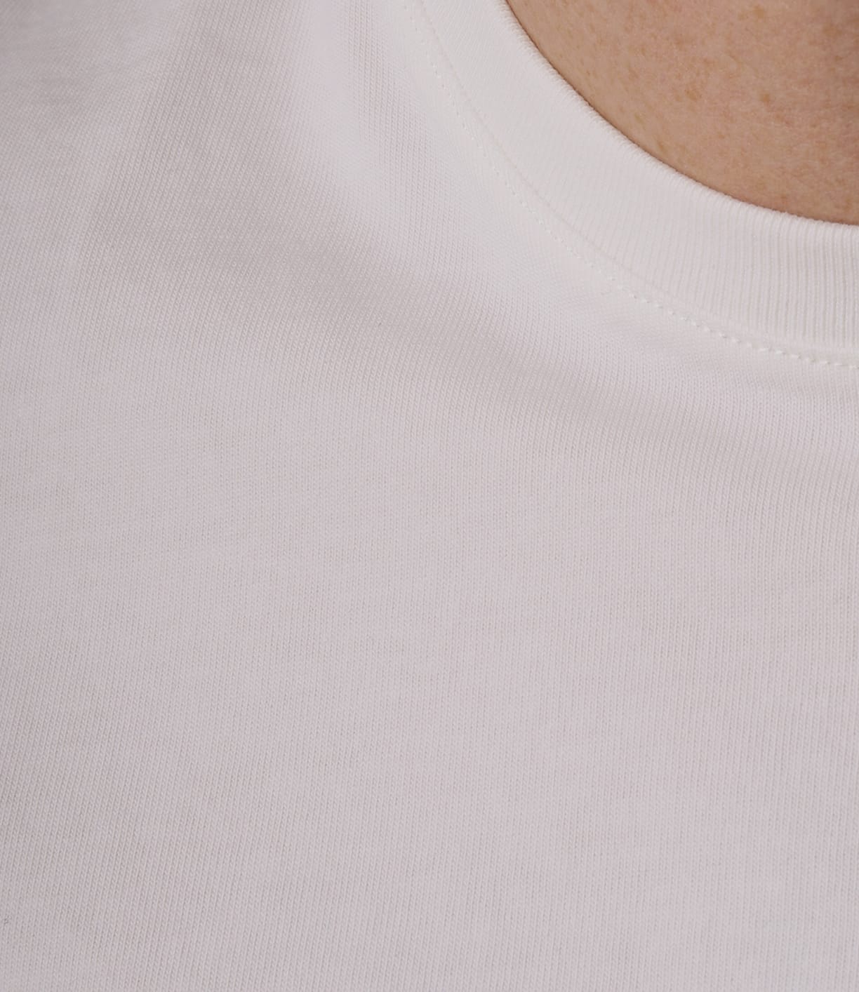 Close-up of a person wearing the Best Made Co. Standard T-Shirt Undyed. The image highlights its soft texture and classic neckline, with part of the wearer’s neck and shoulder shown in the top right corner.