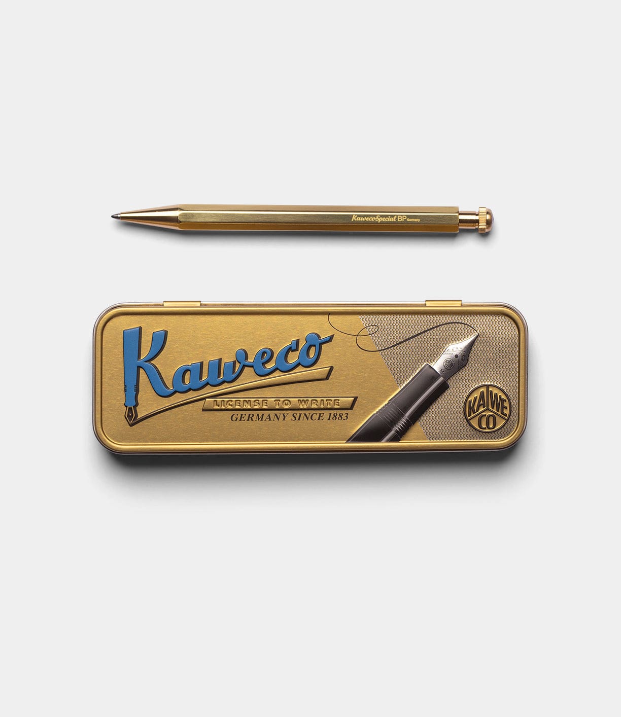 A gold Best Made Co. Kaweco Special mechanical pencil with an octagonal design rests above a matching gold metal tin featuring blue and black accents, all set against a plain white background.