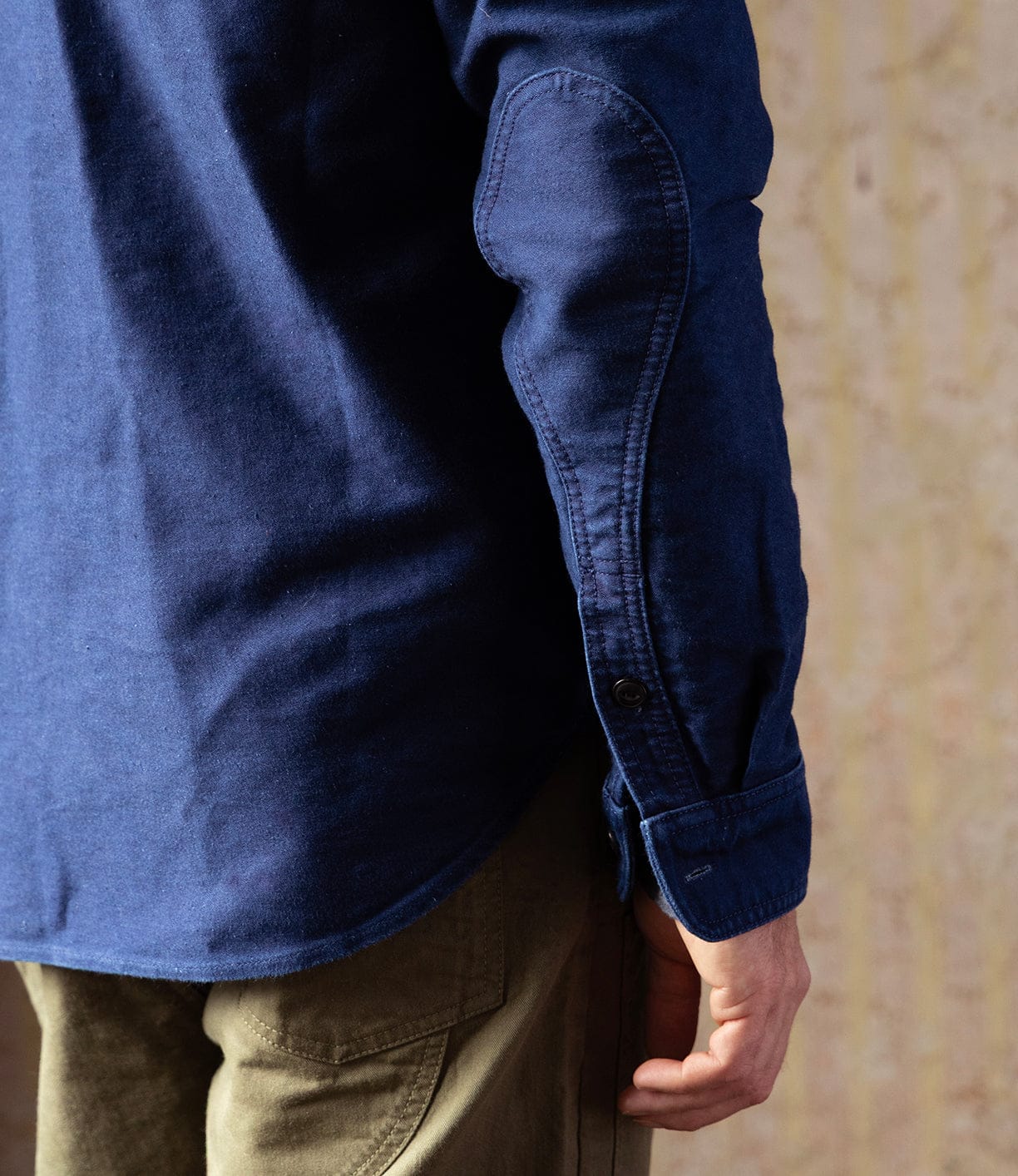 A person wears the Best Made Co Indigo Moleskin Work Shirt with olive green pants, viewed from the back and side, their arm relaxed at their side.