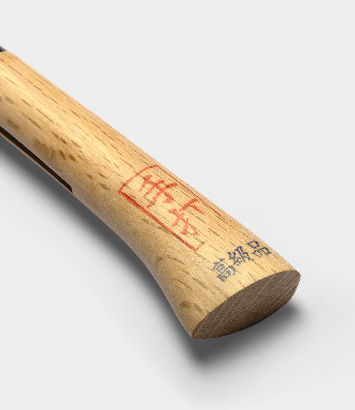 A close-up of the wooden handle of the Best Made Co Japanese Hatchet, featuring red and black stamped characters, photographed against a plain white background.