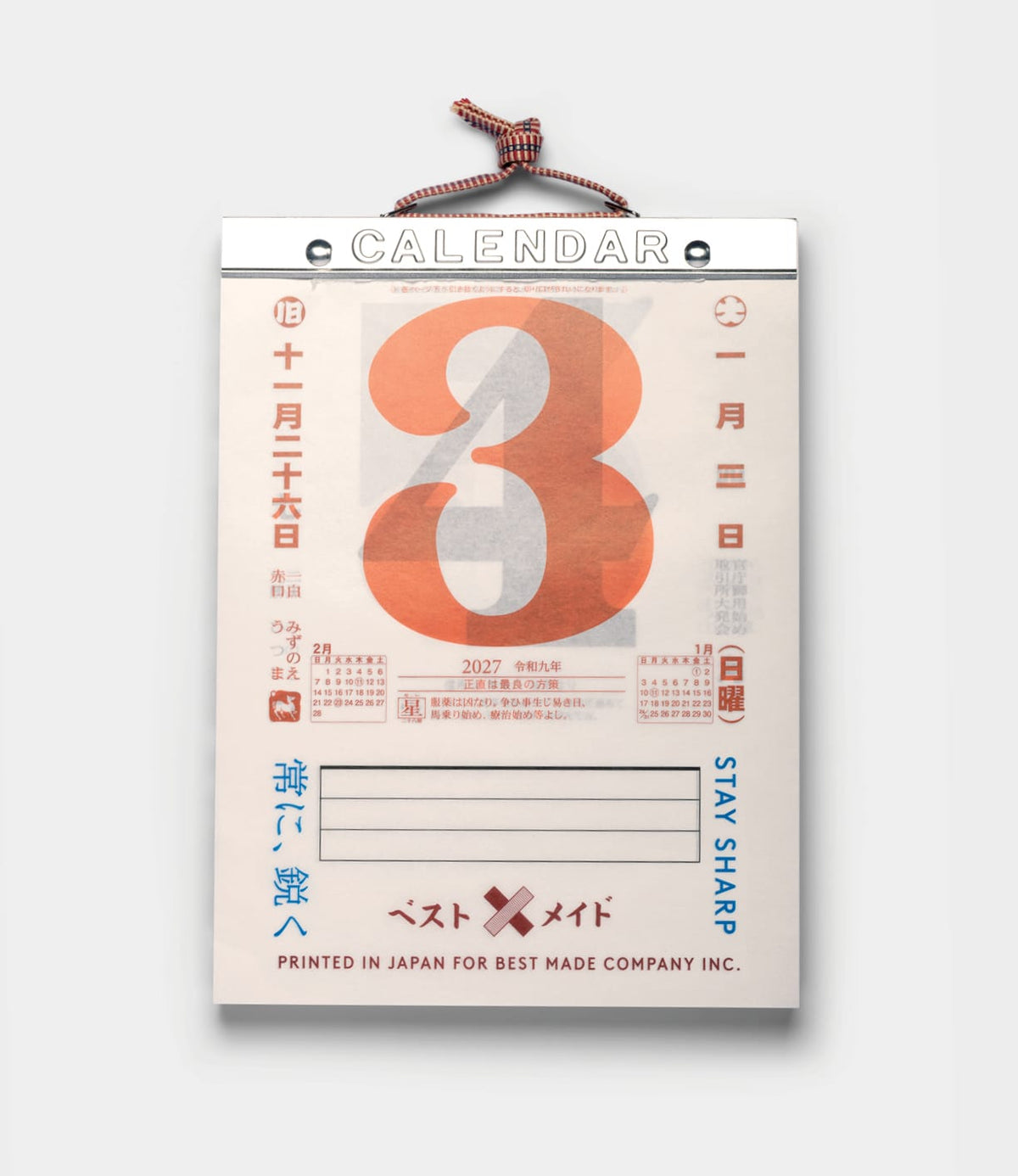 A Best Made Co. Himekuri Calendar 2027 hanging from a cord, featuring a large orange number three above a small monthly grid and Japanese text on a white card.