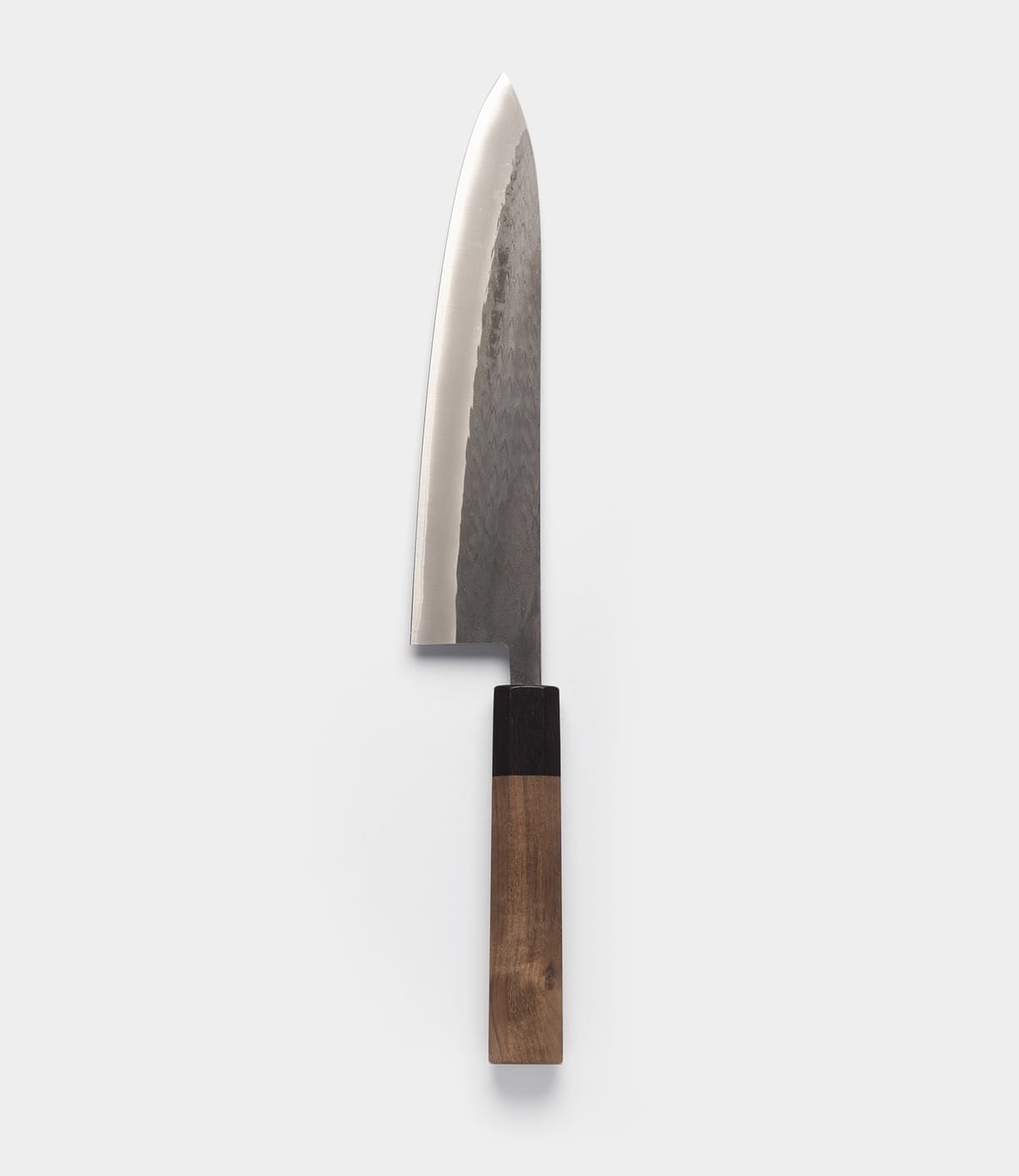 A vertical studio shot of the Aogami Gyuto Knife by Best Made Co. against a plain white background. This gyuto knife showcases a polished, dark-textured blade—expertly forged from Blue Paper Steel No. 2—and features a two-toned wooden handle.