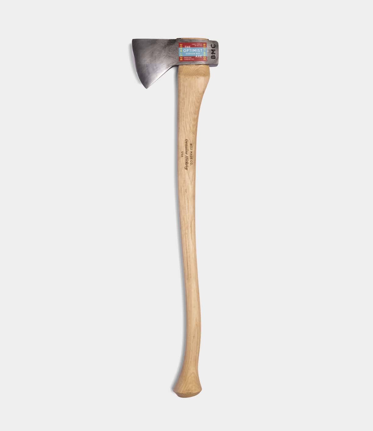 The Optimist by Best Made Co. is a single-bladed Hudson Bay axe featuring a 5160 carbon steel head and a long, curved wooden handle, shown on a plain white background with a label attached near the top of the metal head.