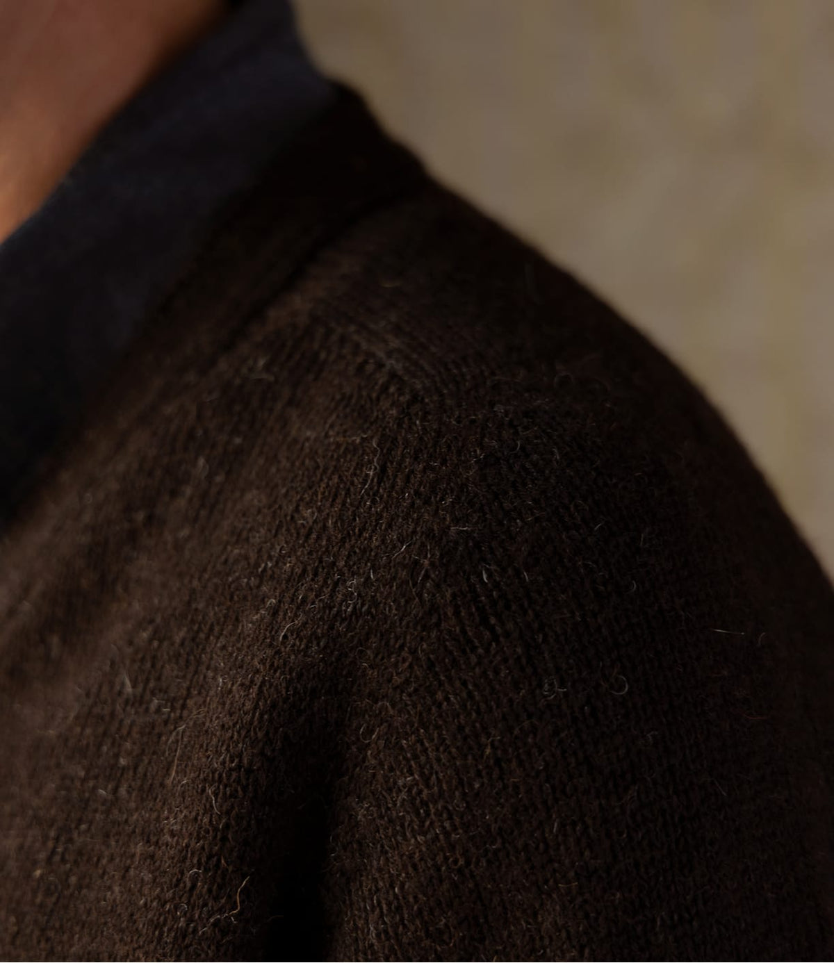 Close-up of the shoulder of an undyed Shetland wool Black Sheep Cardigan worn over a dark shirt.