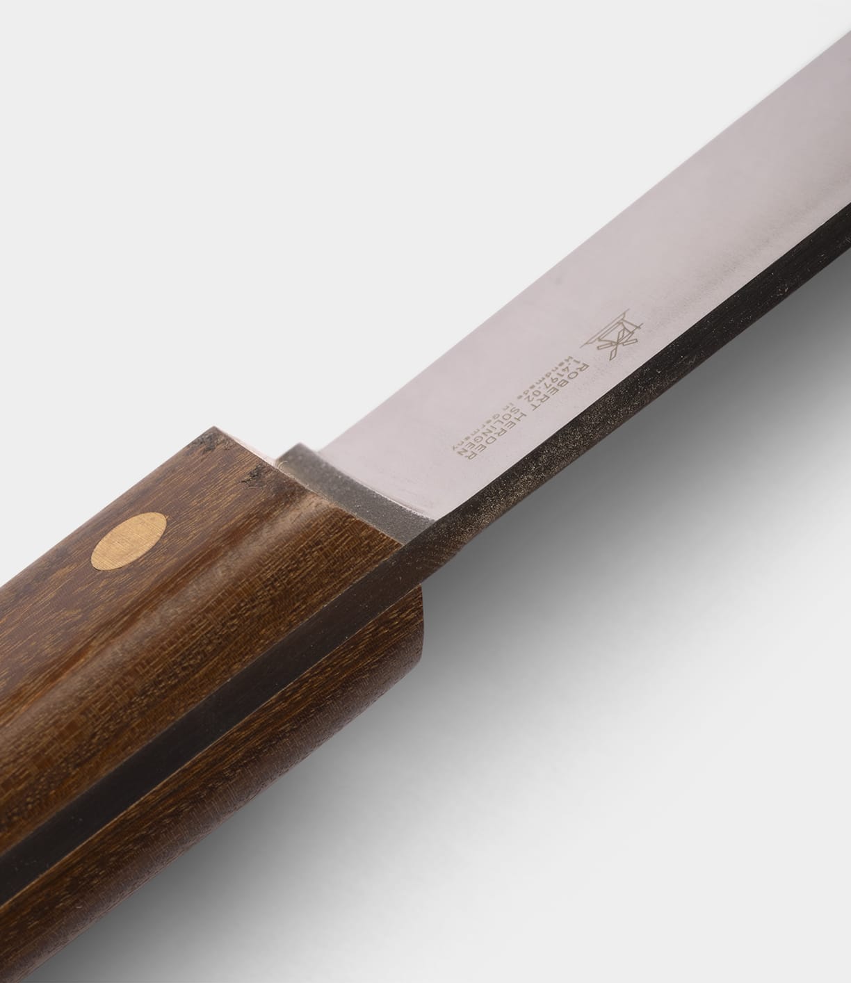 Close-up of the Best Made Co. Sailor’s Knife, featuring a Brazilian Teak handle and a polished Niolox steel blade with engraved text and symbols near the handle.