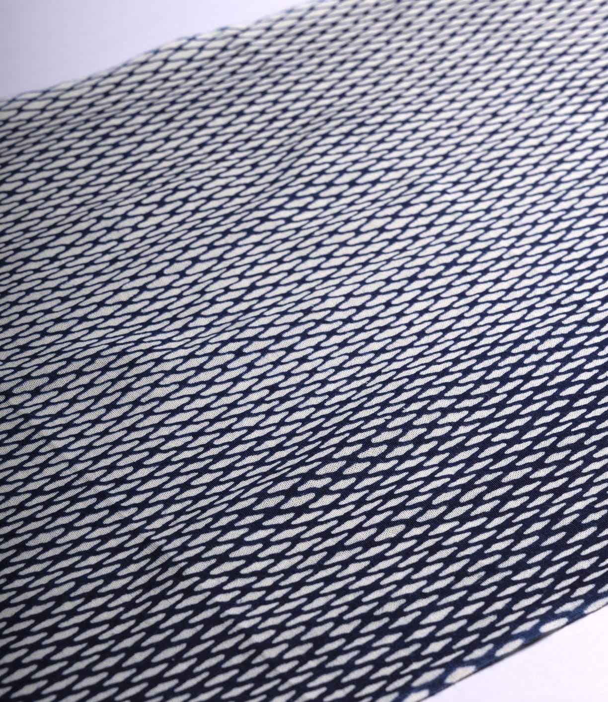 The Ami Net Tenugui by Best Made Co. is a hand-dyed Japanese cloth with a repeated diagonal navy and white elongated diamond pattern, showcasing wabi-sabi beauty when laid flat on a white surface.