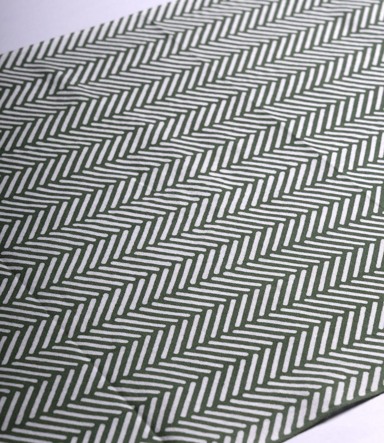 A close-up of the Sugi-Aya Tenugui by Best Made Co., showcasing hand-dyed Japanese fabric with green and white herringbone stripes in a wabi-sabi zigzag pattern.