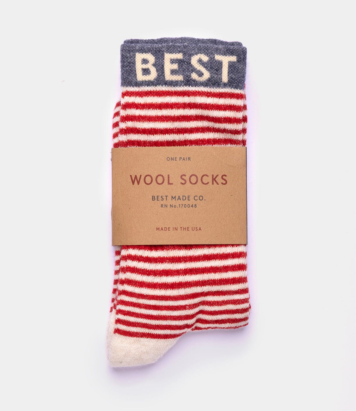 A pair of red and white striped Standard Wool Socks with a gray cuff reading "BEST," from Best Made Co—quality American-made socks for everyday wear, wrapped in a brown paper label marked "WOOL SOCKS, BEST MADE CO., MADE IN THE USA.