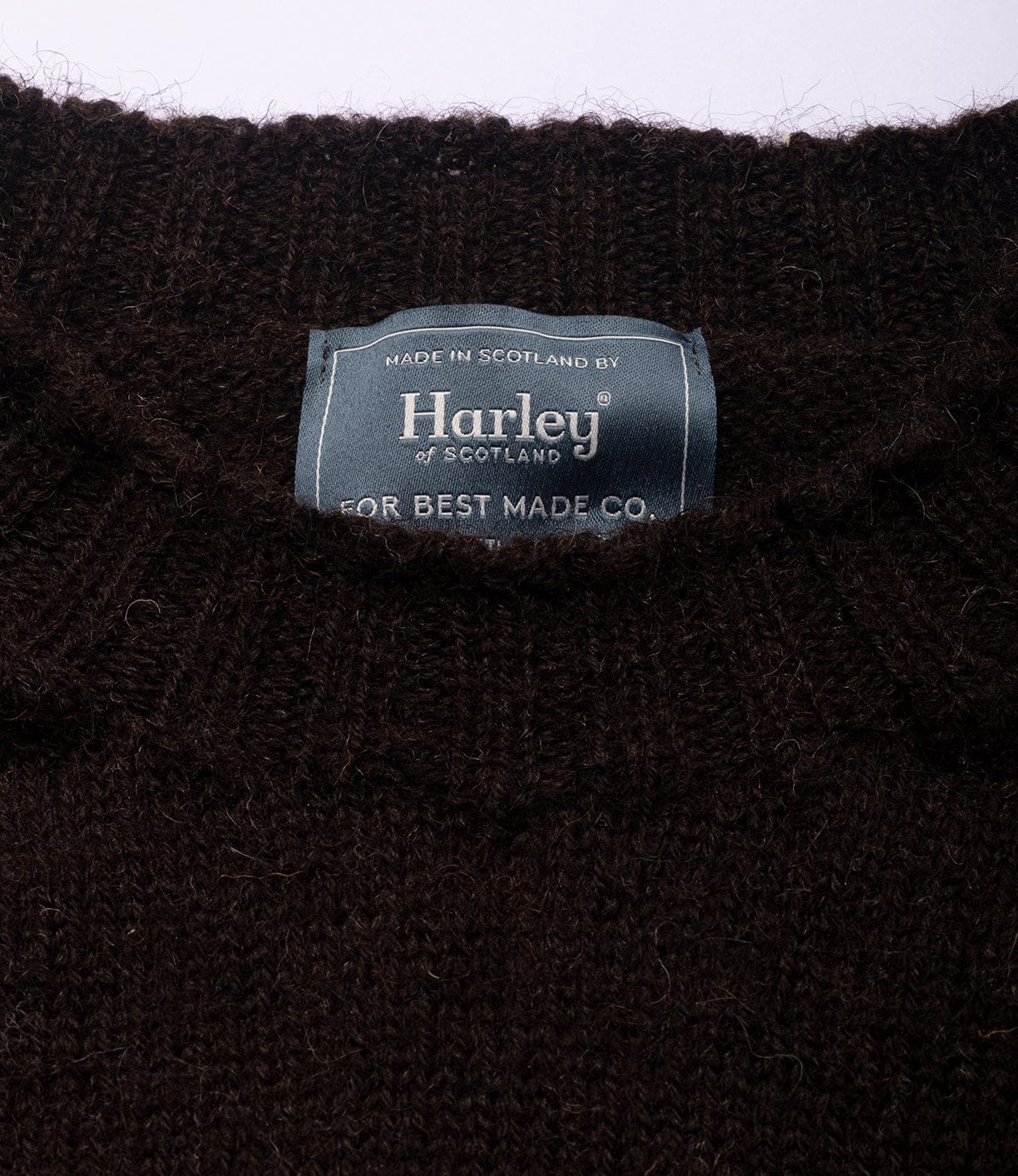 Close-up of Best Made Co.'s Black Sheep Sweater, crafted in Scotland from undyed black Shetland wool with seamless construction. Label reads Harley of Scotland for Best Made Co.