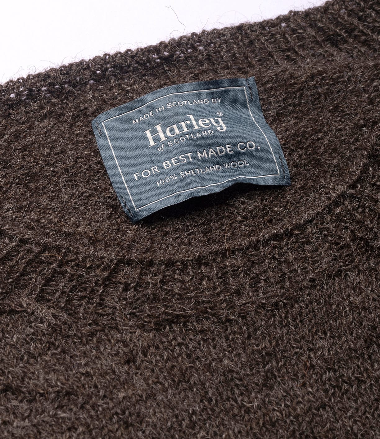 A close-up of the Best Made Co. 5-Gauge Shetland Sweater shows its seamless construction, lightweight warmth, and a label indicating 100% Shetland wool, made in Scotland.