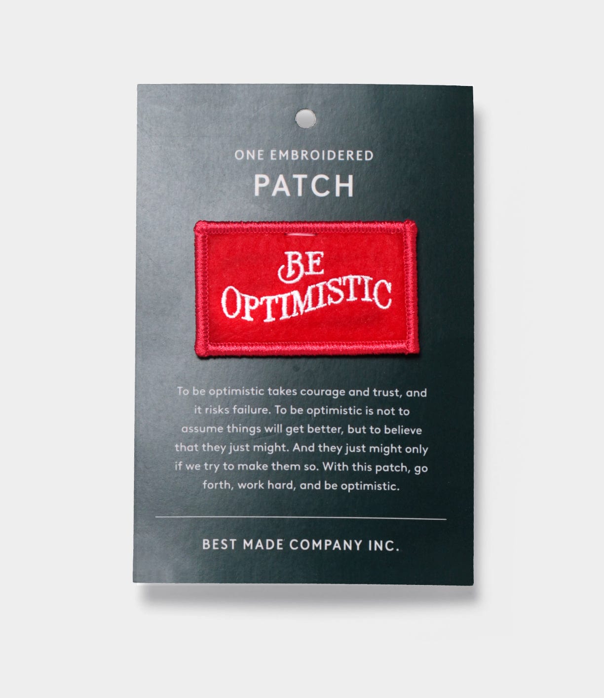 The Be Optimistic Patch by Best Made Co. is a red embroidered accessory on a dark card with an inspiring message—ideal for outdoor retail fans and wilderness survival enthusiasts.