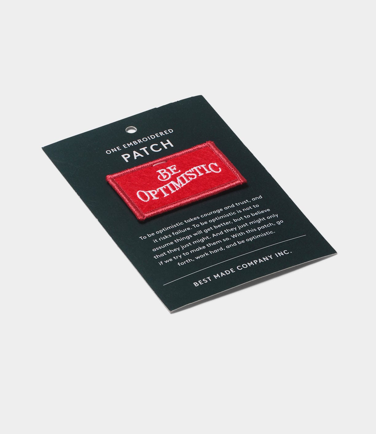 The Be Optimistic Patch by Best Made Co. is a red embroidered patch on a black card with an optimism quote and branding—an ideal accessory for any outdoor retail display or wilderness survival kit.