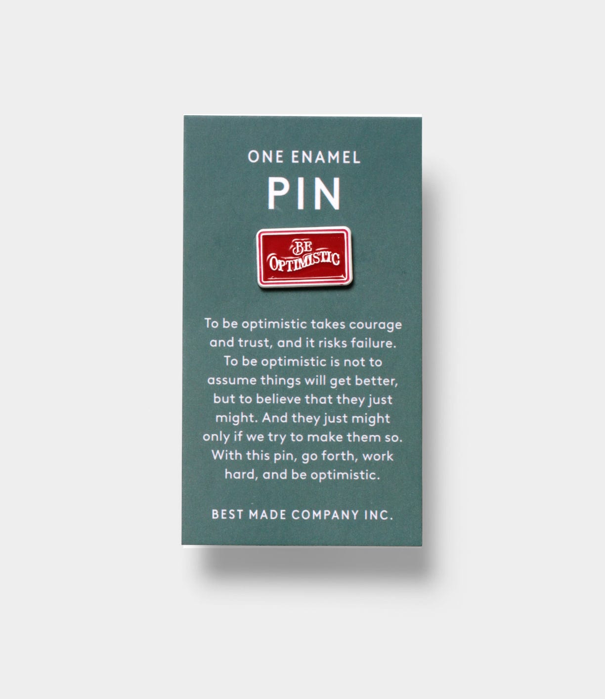 The Be Optimistic Pin by Best Made Co. is a red enamel pin with “Be Optimistic” on it, attached to a card featuring an inspirational optimism quote—an uplifting accessory to boost your mindset.