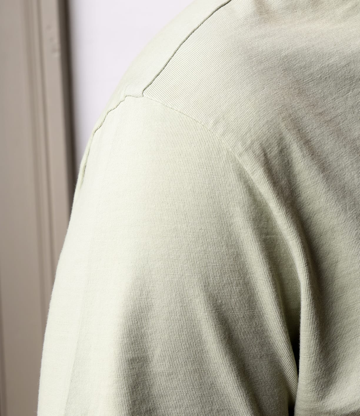 Close-up of a person wearing the Best Made Co. Standard Pocket T-Shirt Haze in light beige. The Peruvian tangüis cotton’s texture and stitching are visible, while an out-of-focus background highlights this durable everyday staple.
