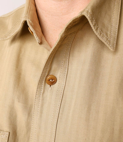A close-up of the Best Made Co. Cotton-Linen Workshirt Tan, highlighting its collar, chest pocket flap, and the detailed texture and stitching of the beige fabric.
