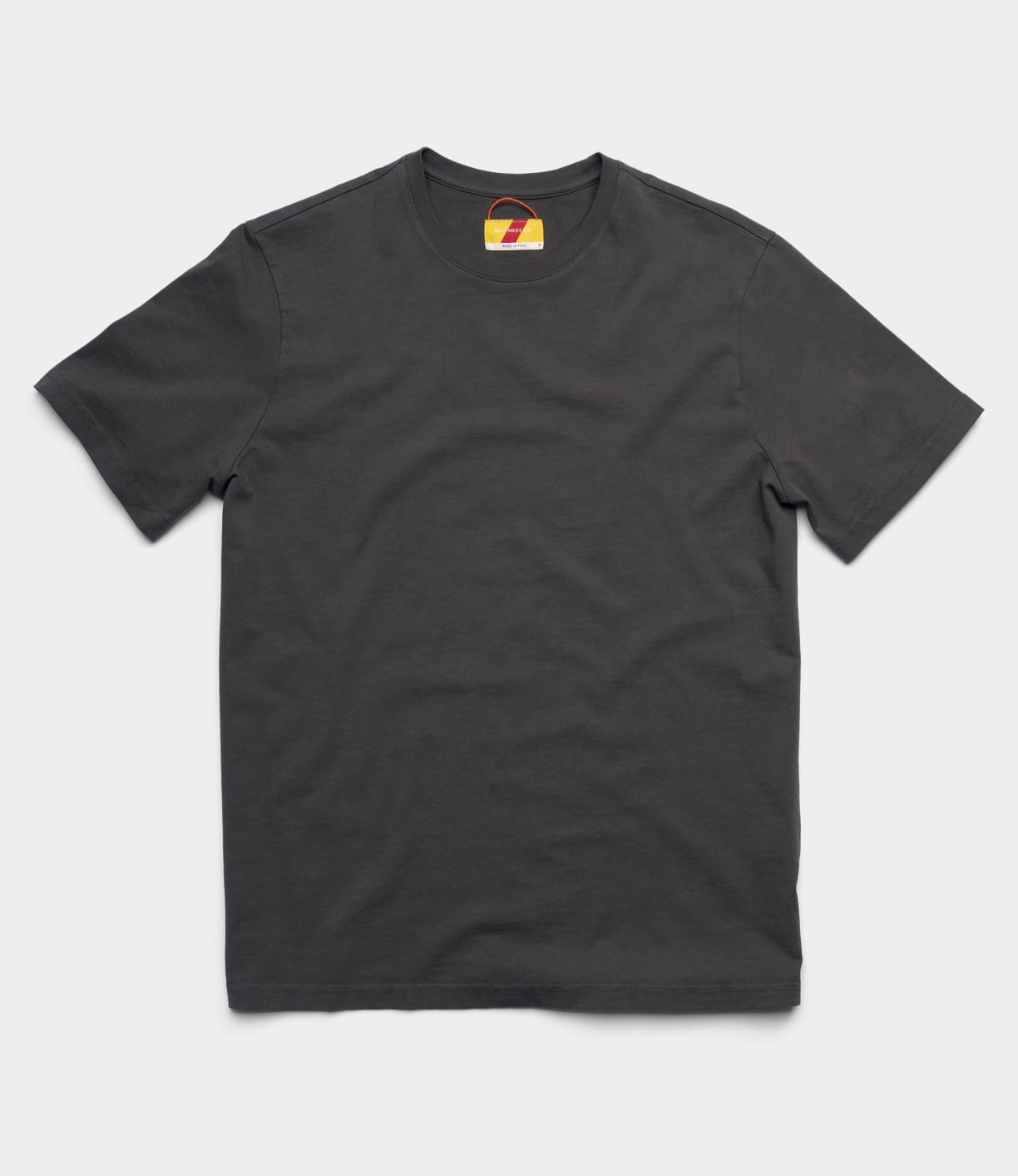 The Best Made Co Standard T-Shirt in Faded Black is a plain, short-sleeve crewneck, shown laid flat on a light gray background. Crafted from soft Peruvian tangüis cotton, this staple features no logos and has a discreet collar tag.