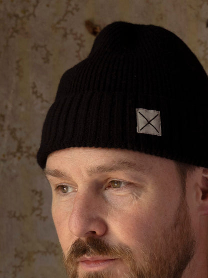 Best Made Co. Cap of Courage in black lambswool, featuring a ribbed knit and a small square patch with an X logo on the side.