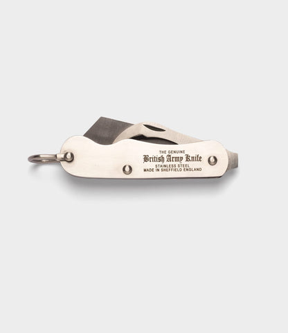A closed Best Made Co. British Army Knife, made of stainless steel and engraved with "THE GENUINE British Army Knife STAINLESS STEEL MADE IN SHEFFIELD ENGLAND," rests on a light gray background.