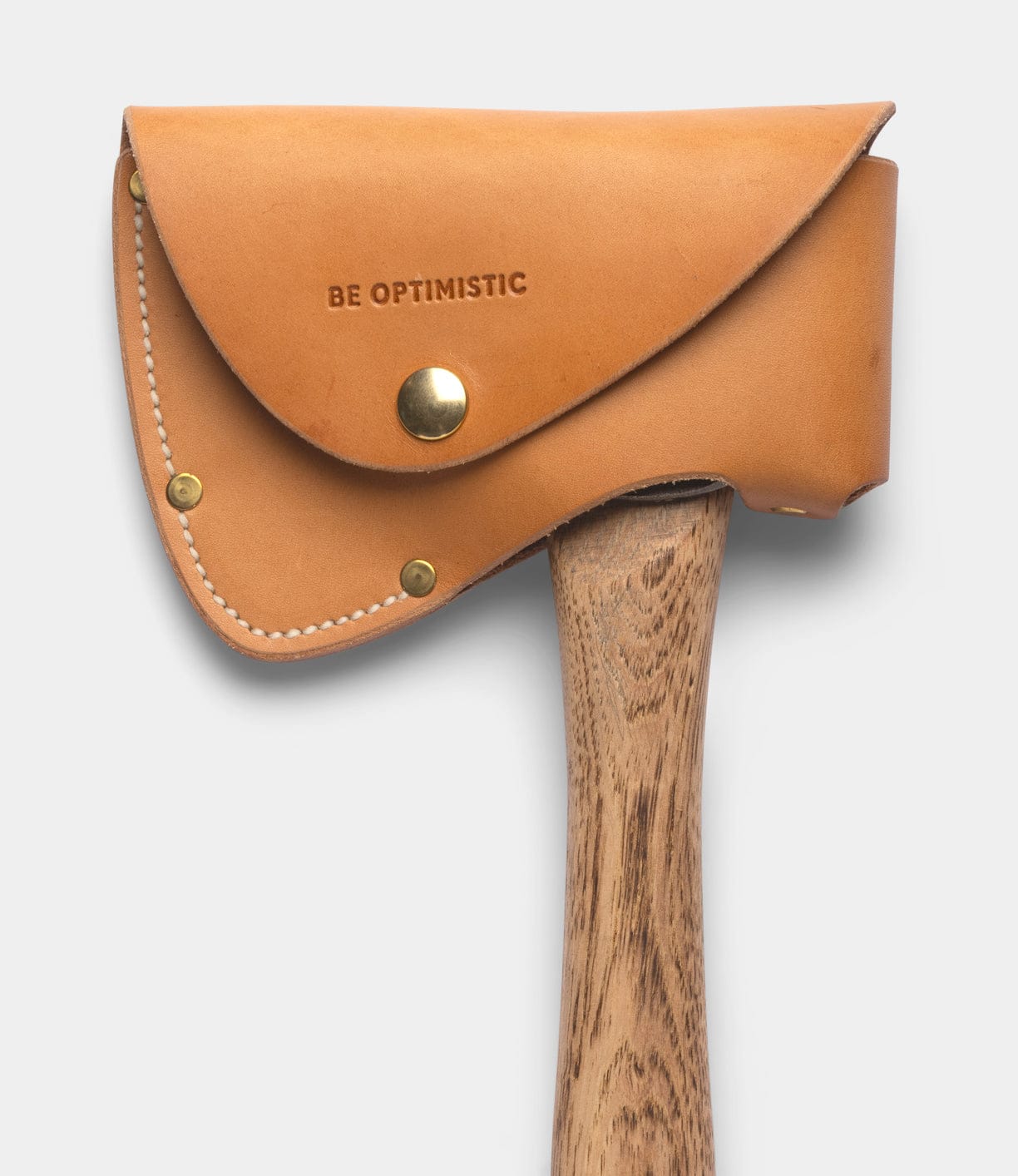 The Best Made Co. Spark (Straight-Hold Edition) campfire axe features an Appalachian hickory handle and a tan leather blade cover stamped with "BE OPTIMISTIC" and secured by brass rivets, set against a plain light gray background.