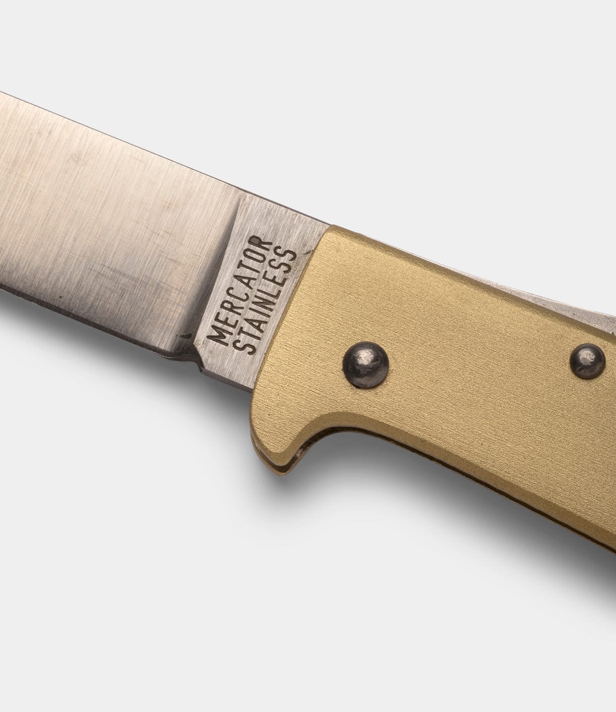 Close-up of the Brass Mercator by Best Made Co, showing its metallic blade engraved MERCATOR STAINLESS and brass handle with rivets, set against a plain white background.