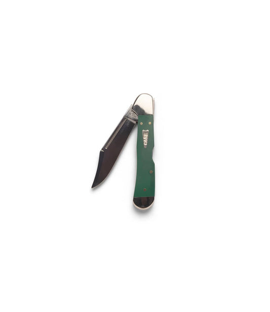 A person holds a Best Made Co Mini Copperlock knife above a whetstone, ready to sharpen the blade on a green cutting mat with yellow grid lines.