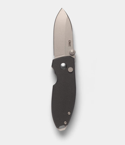 A Best Made Co. CRKT Squid pocket knife with a textured black handle, short wide silver D2 blade, button lock mechanism, and partially open design. The CRKT logo is engraved on the blade.