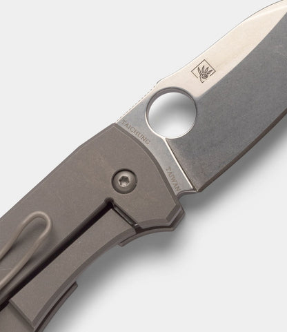 Close-up of a Best Made Co. Spyderco Techno 2 pocket knife with a partially open CTS-XHP steel blade, round thumb hole, titanium framelock handle, and "TAICHUNG TAIWAN" etched near the pivot on a plain light background.