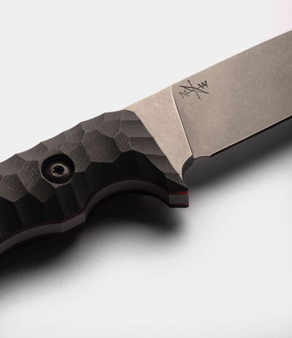 A close-up of the Best Made Co. NWBW Field Knife (BMC Edition) showcases its textured black handle and matte silver D2 tool steel blade with an engraved signature near the spine, set against a plain white background.