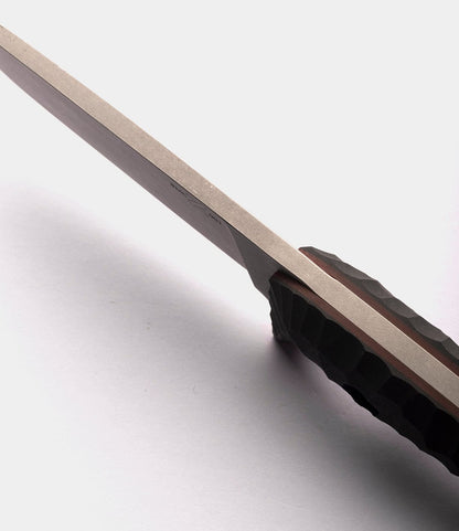 Close-up side view of a Best Made Co. NWBW Field Knife (BMC Edition), featuring a textured dark handle and highlighting the edge and thickness of its D2 tool steel blade against a light gray background.