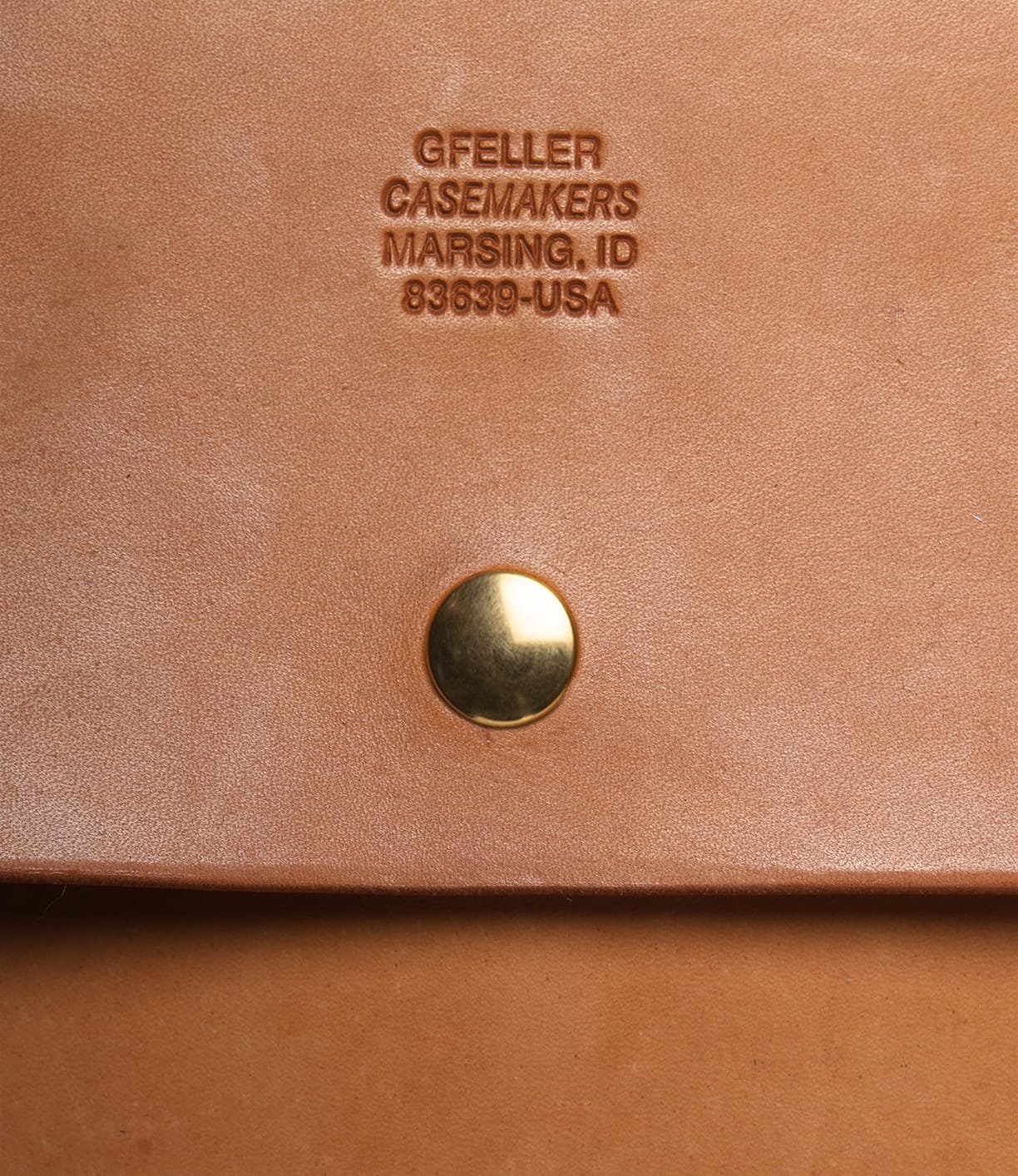 Close-up of the Best Made Co. Gfeller Case Large in American russet skirting leather, featuring a gold snap button and embossed text reading GFELLER CASEMAKERS MARSING, ID 83639-USA.