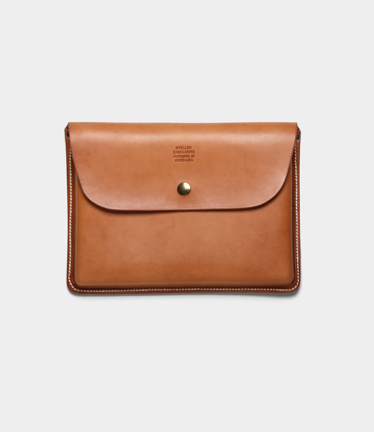 The Best Made Co. Gfeller Case Small is a tan leather envelope-style document case with white hand-stitched edges, a brass button closure, and minimal text embossed near the top center.