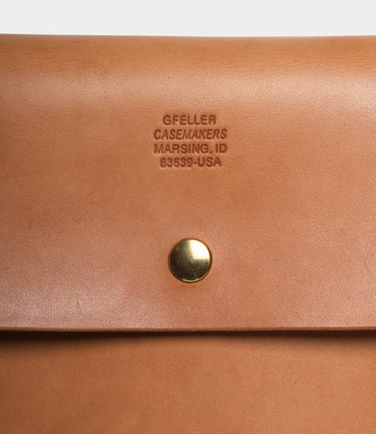 Close-up of the tan Gfeller Case Small by Best Made Co. with a gold snap button and "GFELLER CASEMAKERS MARSING, ID 83639-USA" embossed above it on this hand-stitched leather case.