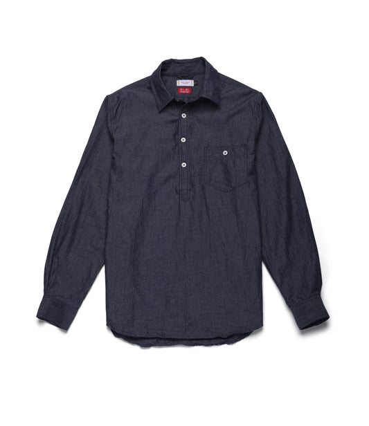 The Best Made Co. Indigo Chambray Popover is a long-sleeve, dark blue chambray woven shirt featuring a partial button placket, single chest pocket, and buttoned cuffs, shown laid flat on a light background.