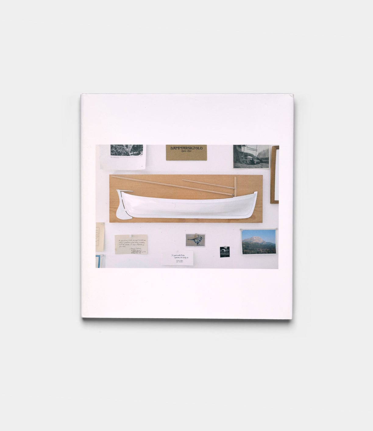 The "Boats, Books, Birds" by Best Made Co. is a framed display with a white hand-carved wooden boat on beige, artfully surrounded by photos, postcards, and documents.