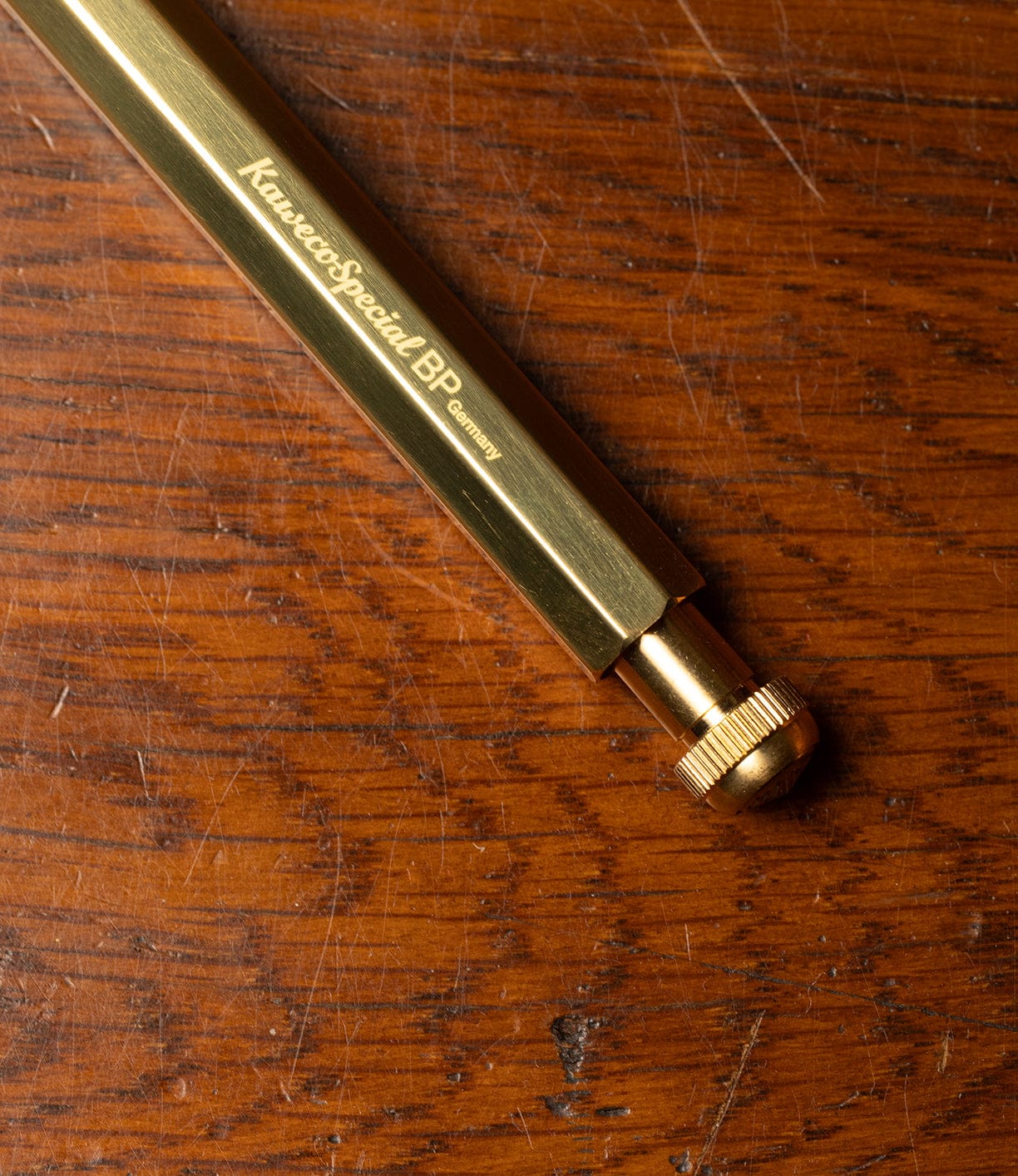 A Best Made Co. Kaweco Special ballpoint pen with its signature octagonal design lies on a scratched wooden surface.