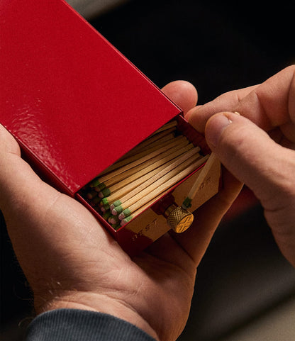 Hands sliding a red Best Made Co. Sliding Match Safe open to reveal a row of strike-anywhere matches.
