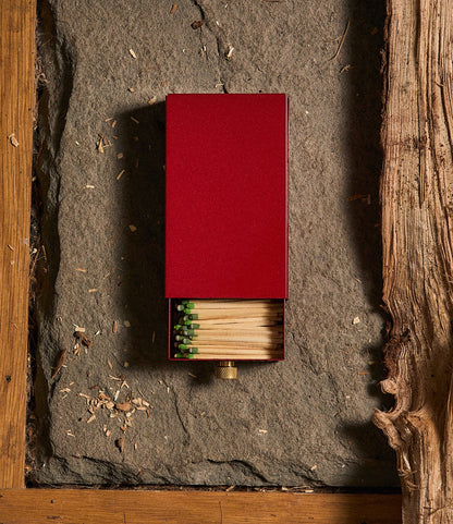 A red Sliding Match Safe Red partially open to reveal wooden strike-anywhere matches with green tips.