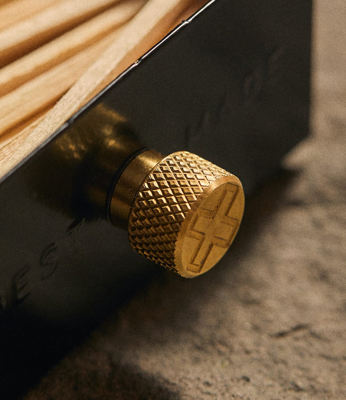 Close-up of a Best Made Co. Sliding Match Safe Black, featuring a black metal sliding case holding wooden matches and a knurled brass knob with an embossed cross symbol.
