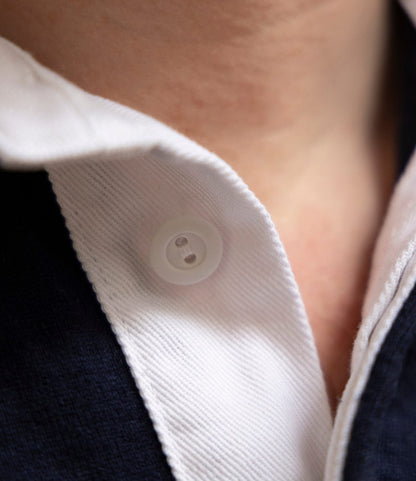 Close-up of the McArthur Rugby Jersey by Best Made Co.—a white collared shirt with button fastened, layered over navy. Only neck, collar, and button visible. Crafted from heavyweight cotton jersey for lasting comfort.