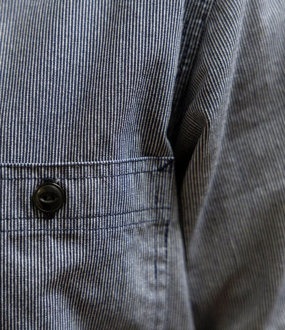 Close-up of the Best Made Co. Indigo Stripe Workshirt, crafted from Portuguese cotton with visible triple-needle stitching, a black-buttoned pocket, and clear vertical stripes.