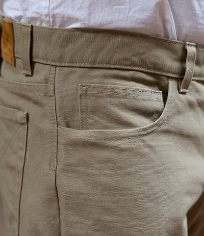 Close-up of a person wearing Best Made Co. Standard 5-Pocket Pant Tan with a white shirt tucked in. The versatile canvas pants feature a visible waistband, belt loop, front pocket, and straight-leg design.