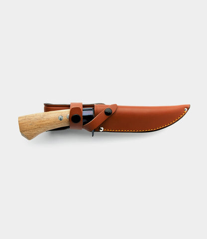 The Hotta San Hunting Knife by Best Made Co. features a handmade fixed blade and wooden handle, secured in a brown leather sheath with snap closure, shown on a plain white background.