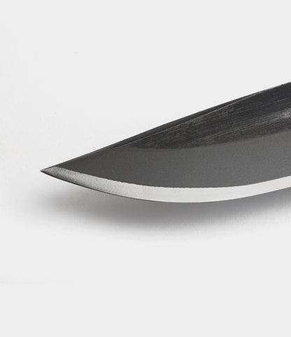 Close-up of the pointed tip and sharp edge of the Best Made Co. Hotta San Hunting Knife, a handmade blade crafted from Yasuki blue steel, set against a plain white background.