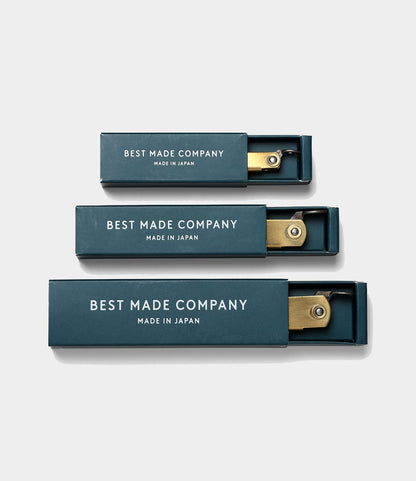 Three brass folding rulers in navy blue boxes labeled Best Made Co. are arranged by size on a light gray background. Each box, resembling the Max Brass Higo Knife case, is partially open to show the ruler inside.