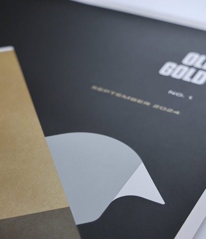 A close-up of a magazine cover titled OLD GOLD, issue 1, September 2022 in gold text. Partially overlapping is Best Made Co.’s “Good as Gold” Silk-Screened Poster, featuring a geometric white and gold design.