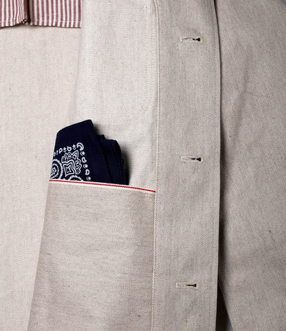 Close-up of the Best Made Co. Selvedge Natural Studio Jacket, featuring organic cotton-hemp fabric, visible buttonholes, a navy patterned pocket square in the chest pocket, and red edge stitching—a true example of American craftsmanship.