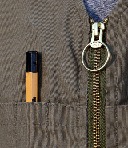 A close-up of Best Made Co.’s PB-S’s Utility Vest Black, featuring a gold zipper with ring pull and crafted from Japanese cord fabric. A pen with a black cap is tucked into one of the vest’s chest pockets.