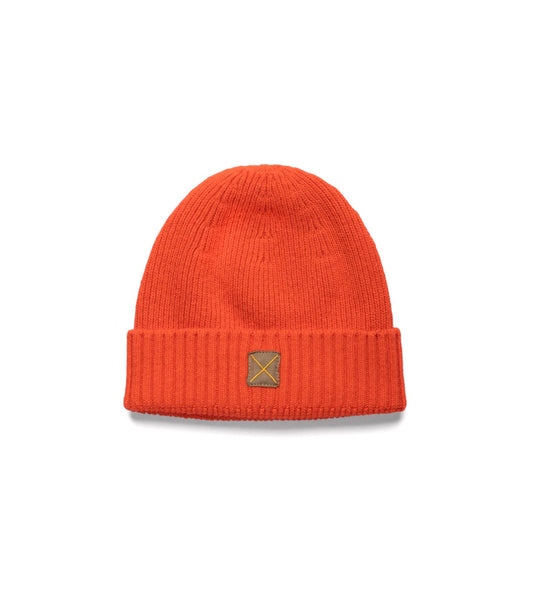 The Cap of Courage by Best Made Co is an orange knit lambswool cap with a folded brim and a small brown rectangular front patch, shown against a plain white background.