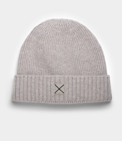 The Cap of Courage by Best Made Co. is a light gray lambswool ribbed knit beanie with a folded brim, featuring a white patch and black X design—shown here on a plain white background.